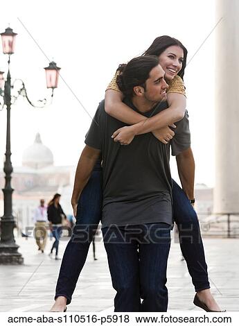Stock Photo - Italy, Venice, Young man giving piggyback ride to woman on St. Mark's Square. Fotosearch