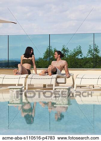 Italy, Young couple relaxing by swimming pool View Large Photo Image Stock Image - Italy, Young couple relaxing by swimming pool. Fotosearch