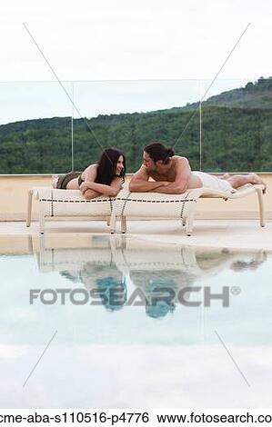 Italy, Young couple relaxing by swimming pool View Large Photo Image Stock Photograph - Italy, Young couple relaxing by swimming pool. Fotosearch