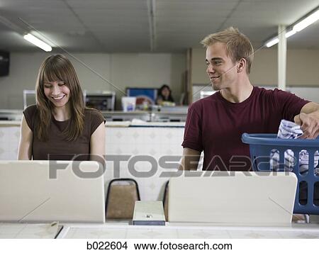 Picture - man and woman at a laundromat. Fotosearch