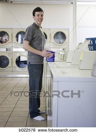 Stock Photo - man doing laundry at a laundromat. Fotosearch