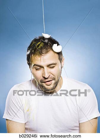 Stock Image - man getting an egg dropped on his head. Fotosearch