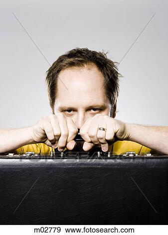 Stock Photo - man hiding behind his briefcase. Fotosearch