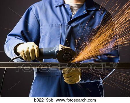 Stock Image - man in blue coveralls with a power grinder. Fotosearch