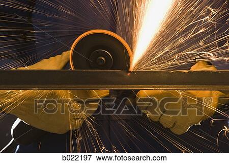 Stock Photo - man in blue coveralls with a power grinder. Fotosearch
