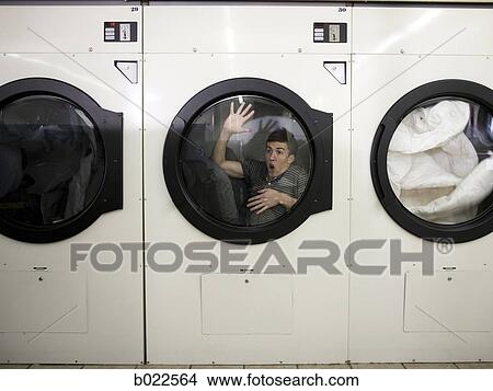 man inside a commercial clothes dryer at a laundromat View Large Photo Image Picture - man inside a commercial clothes dryer at a laundromat. Fotosearch