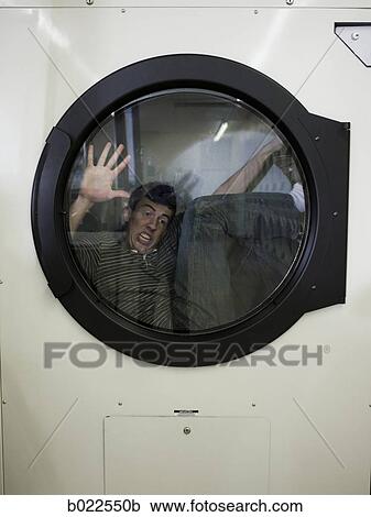 Stock Image - man inside a commercial clothes dryer at a laundromat. Fotosearch