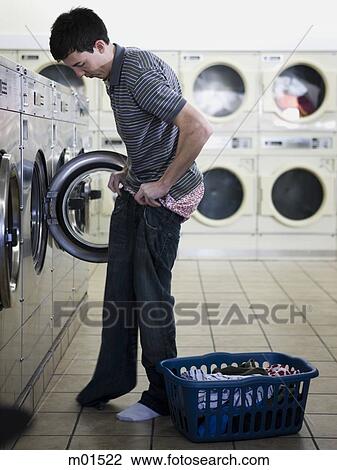 Stock Image - man taking off clothes at a laundromat. Fotosearch