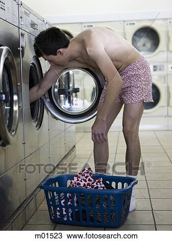 Stock Image - man taking off clothes at a laundromat. Fotosearch