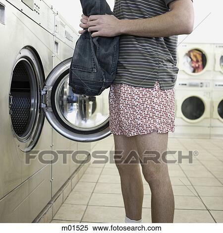 Stock Photography - man taking off clothes at a laundromat. Fotosearch