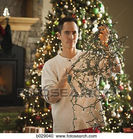 man untangling christmas tree lights View Large Photo Image Stock Image - man untangling christmas tree lights. Fotosearch