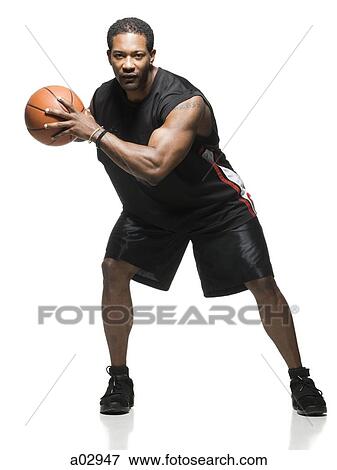 Stock Photo - Mid adult man holding basketball in air, portrait. Fotosearch