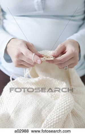 Stock Photo - Mid adult pregnant woman knitting, mid section . Fotosearch