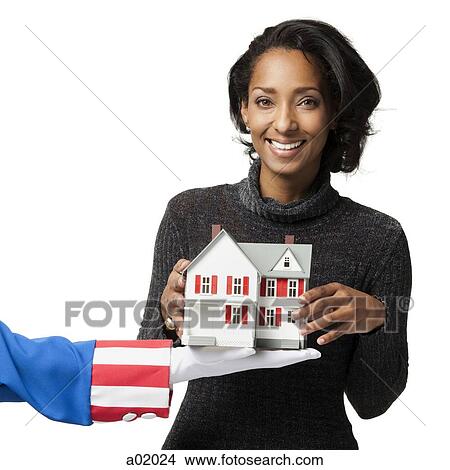 Mid adult woman holding model house, studio shot View Large Photo Image Picture - Mid adult woman holding model house, studio shot. Fotosearch
