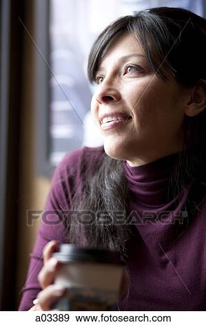 Stock Photo - One mid adult woman drinking coffee in cafe. Fotosearch