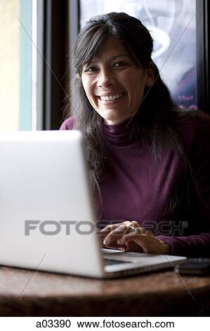 One mid adult woman drinking coffee next to laptop in cafe View Large Photo Image Stock Image - One mid adult woman drinking coffee next to laptop in cafe. Fotosearch
