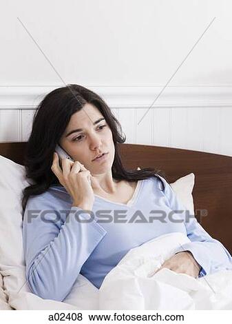 Stock Photo - Orem, Utah, USA, young ill woman in bed talking on cordless phone. Fotosearch