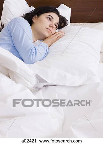 Stock Image - Orem, Utah, USA, young woman lying down in bed. Fotosearch