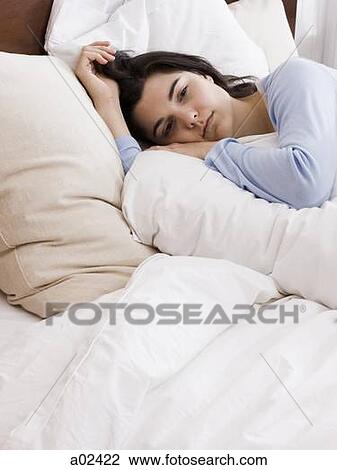 Stock Image - Orem, Utah, USA, young woman lying down in bed. Fotosearch