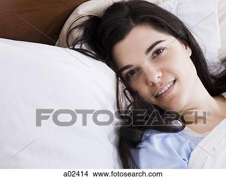 Picture - Orem, Utah, USA, young woman lying in bed smiling, portrait. Fotosearch