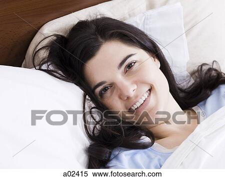 Stock Photography - Orem, Utah, USA, young woman lying in bed smiling, portrait. Fotosearch