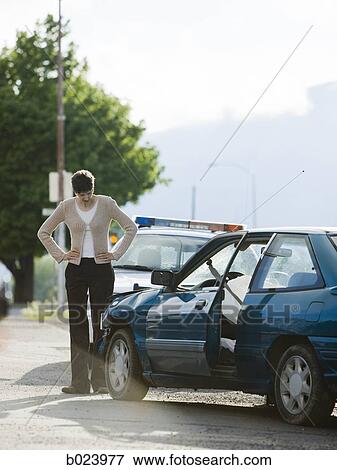 Stock Photo - people looking at a car after an accident. Fotosearch