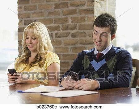 Stock Image - people using cell phones during a meeting. Fotosearch