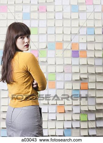 Stock Image - Portrait of young woman looking over shoulder, studio shot. Fotosearch