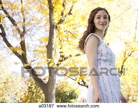 Stock Photo - Provo, USA, Utah, Young woman in front of colorful tree, portrait. Fotosearch
