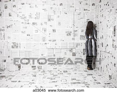 Rear view of young woman standing in corner of newspapers covered room, studio shot View Large Photo Image Stock Photography - Rear view of young woman standing in corner of newspapers covered room, studio shot. Fotosearch