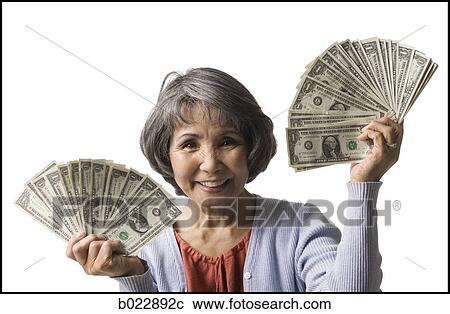 Stock Image - senior woman with hands full of dollars. Fotosearch