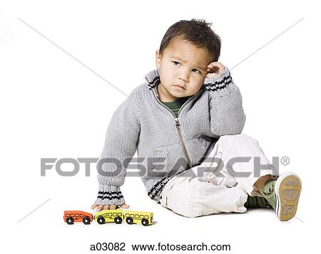 Stock Image - Studio portrait of boy (18-23 months) playing with toy car. Fotosearch