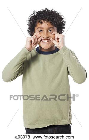 Stock Photo - Studio portrait of boy (8-9) pulling funny face. Fotosearch