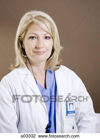 Stock Image - Studio portrait of female doctor using headset. Fotosearch