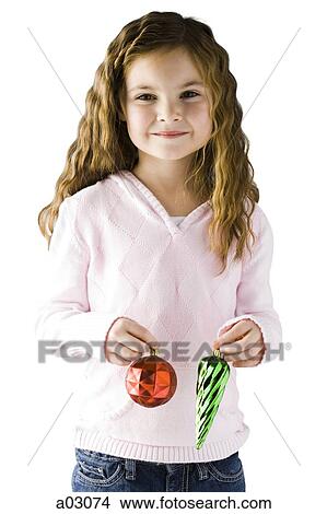 Picture - Studio portrait of girl (6-7) holding Christmas decoration. Fotosearch