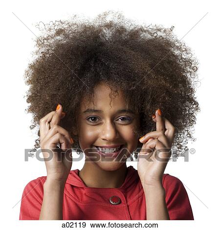 Stock Photo - Studio portrait of teenage girl (12-13) with fingers crossed. Fotosearch