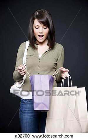 Studio portrait of young woman holding shopping bags View Large Photo Image Stock Image - Studio portrait of young woman holding shopping bags. Fotosearch