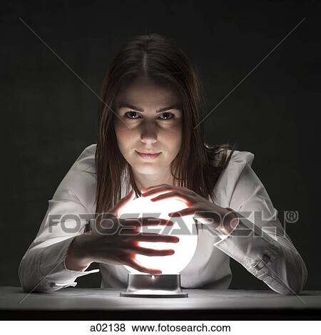 Stock Photo - Studio portrait of young woman holding crystal ball. Fotosearch