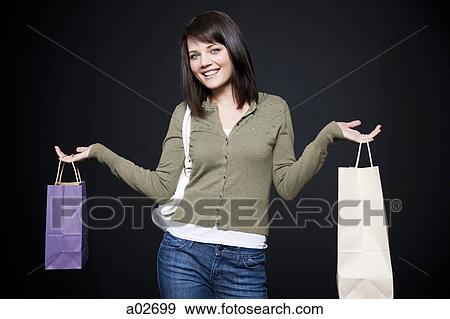 Studio portrait of young woman holding shopping bags View Large Photo Image Stock Photo - Studio portrait of young woman holding shopping bags. Fotosearch