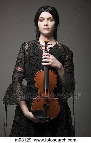 Studio portrait of young woman holding violin View Large Photo Image Stock Photo - Studio portrait of young woman holding violin. Fotosearch