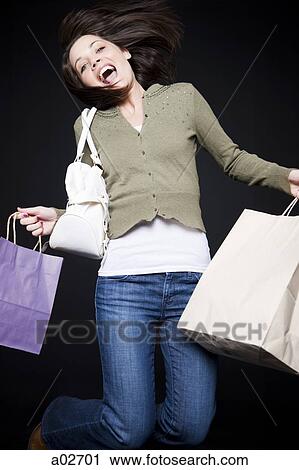 Studio portrait of young woman jumping with shopping bags View Large Photo Image Stock Image - Studio portrait of young woman jumping with shopping bags. Fotosearch