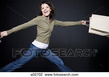 Studio portrait of young woman jumping with shopping bags View Large Photo Image Stock Image - Studio portrait of young woman jumping with shopping bags. Fotosearch