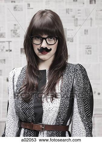 Stock Image - Studio portrait of young woman wearing fake moustache. Fotosearch