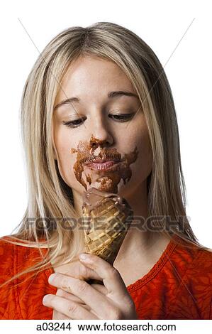 Picture - Studio portrait of young woman with ice cream on face. Fotosearch