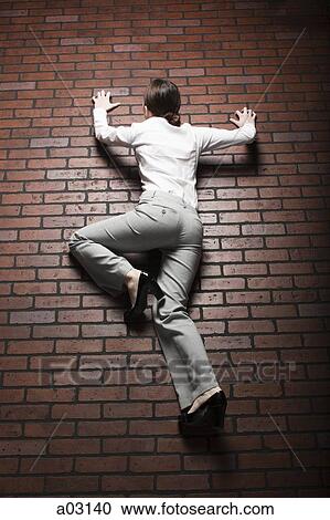 Studio shot of young woman climbing up brick wall View Large Photo Image Stock Image - Studio shot of young woman climbing up brick wall. Fotosearch