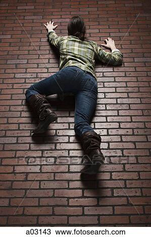 Studio shot of young woman climbing up brick wall View Large Photo Image Stock Image - Studio shot of young woman climbing up brick wall. Fotosearch
