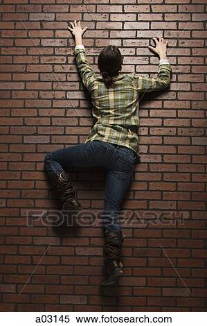 Studio shot of young woman climbing up brick wall View Large Photo Image Stock Photography - Studio shot of young woman climbing up brick wall. Fotosearch