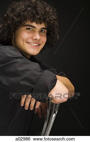 Teenage boy (16-17) sitting backwards on chair, portrait View Large Photo Image Stock Photograph - Teenage boy (16-17) sitting backwards on chair, portrait. Fotosearch