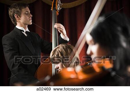 Three young musicians playing in orchestra View Large Photo Image Stock Photo - Three young musicians playing in orchestra. Fotosearch