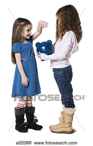 Two girls (4-7) putting money in piggy bank, studio shot View Large Photo Image Stock Photo - Two girls (4-7) putting money in piggy bank, studio shot. Fotosearch